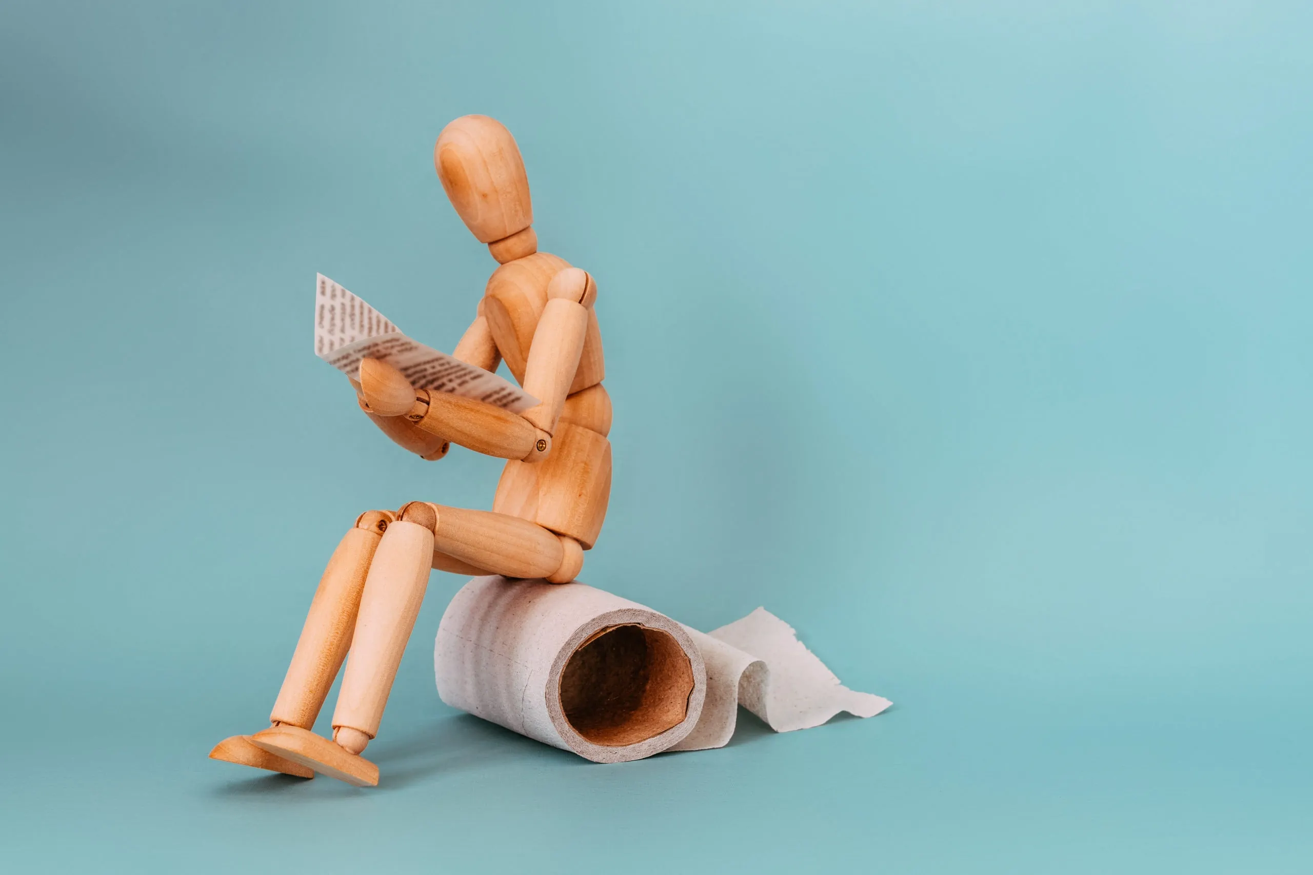 Wooden,figure,sit,on,a,roll,of,toilet,paper,and