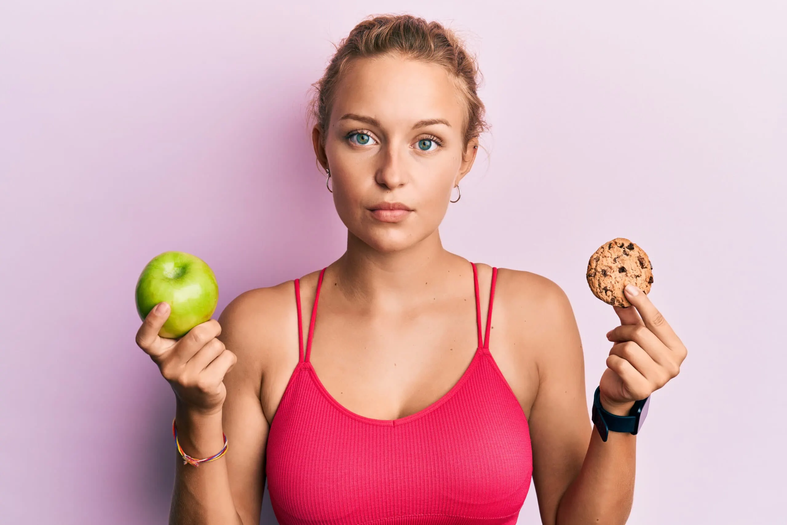 Beautiful,caucasian,woman,holding,green,apple,and,cookie,relaxed,with