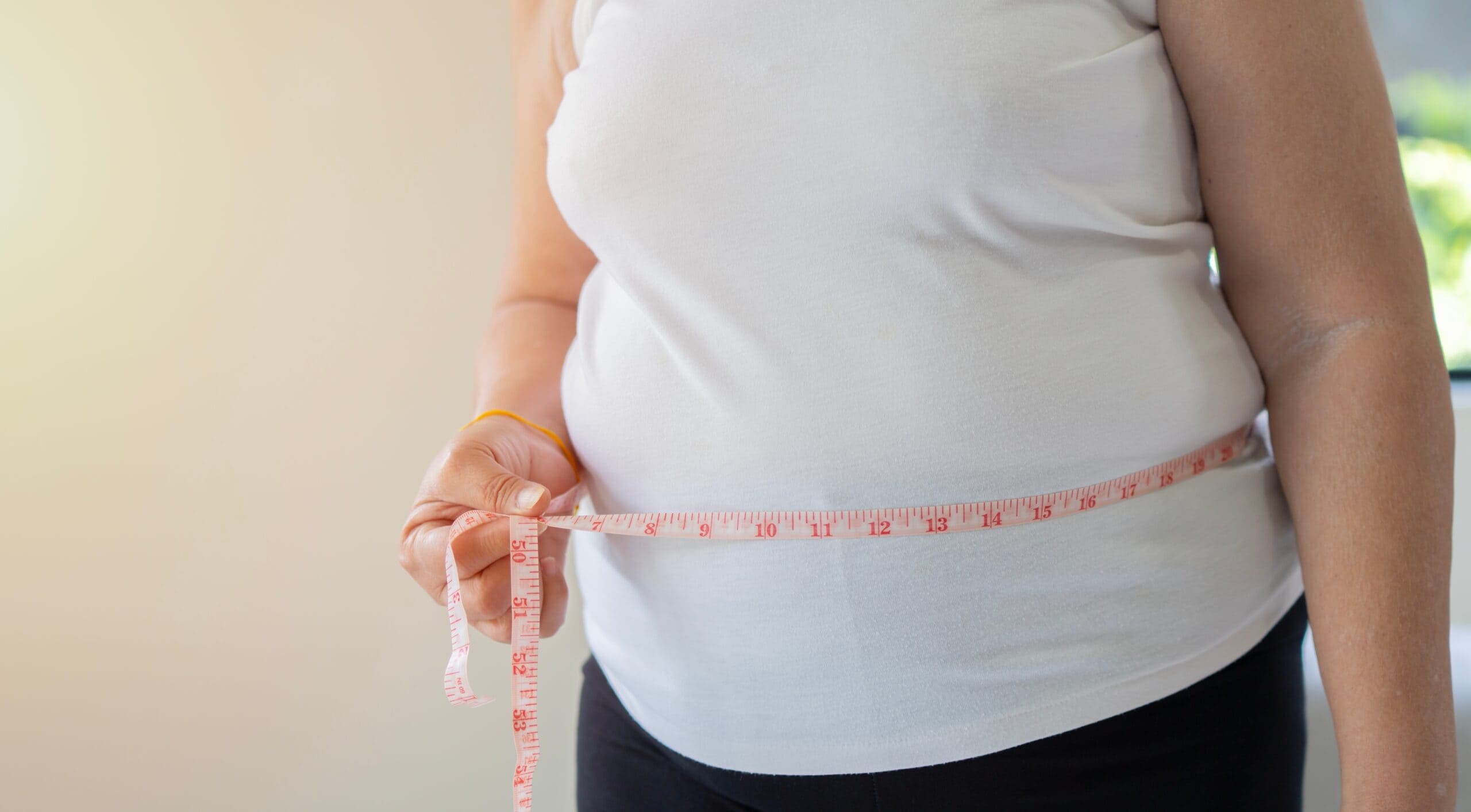 Hands,of,fat,overweight,woman,measuring,her,waist,size,with