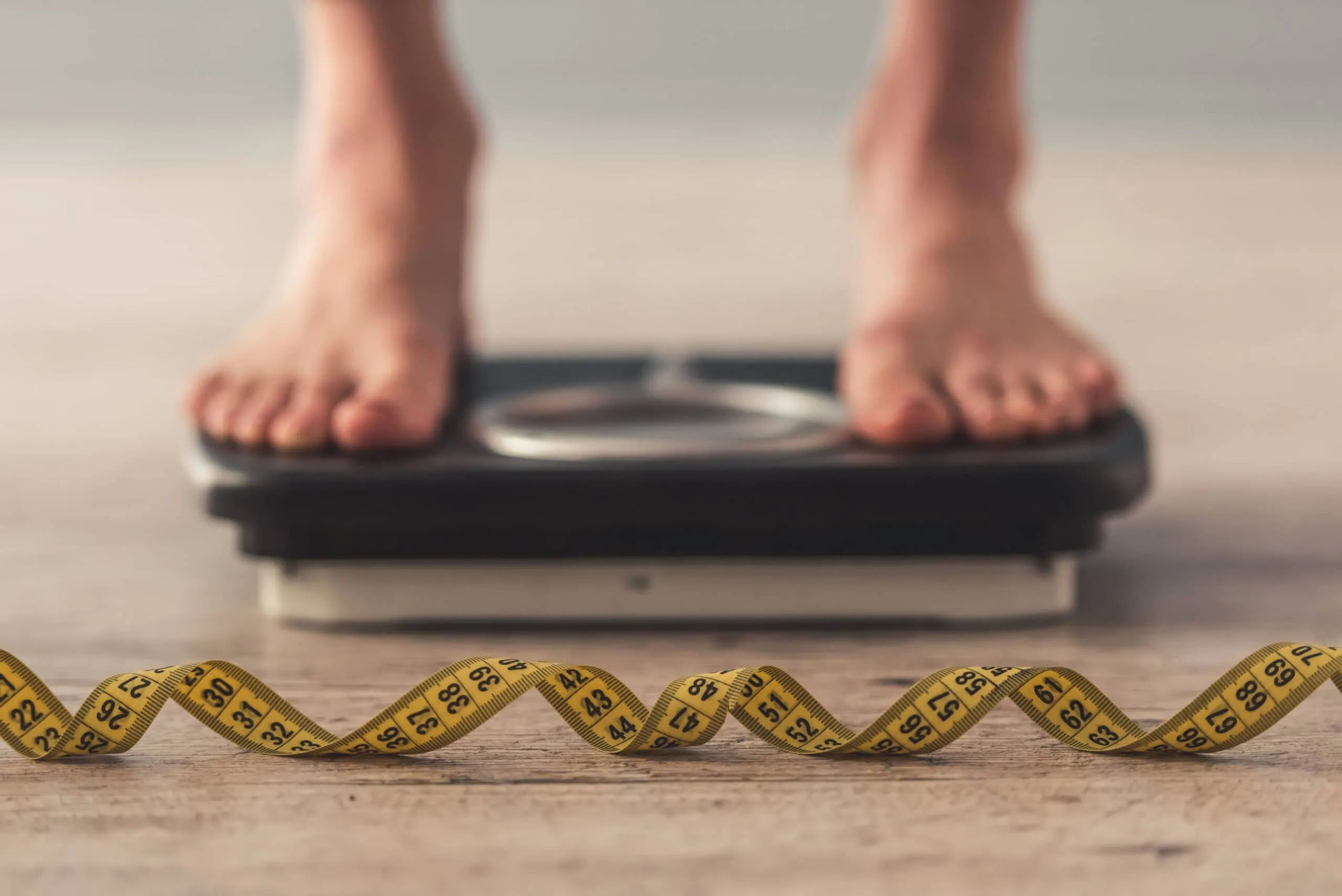 Cropped,image,of,woman,feet,standing,on,weigh,scales,,on
